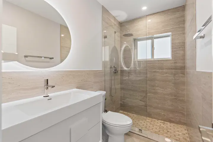 Bathroom with round mirror and walk-in shower